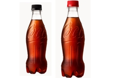 Image Two identical Coca-Cola bottles with red lids placed side by side.
